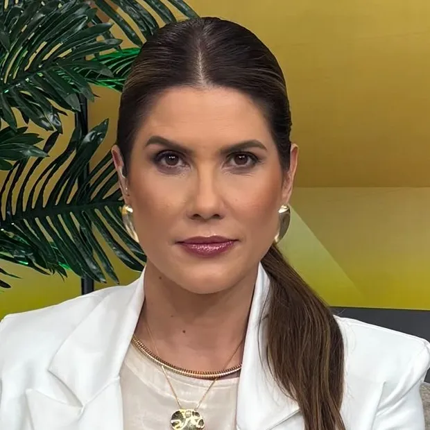 Adriana Reid sorrindo em frente a um microfone de rádio
